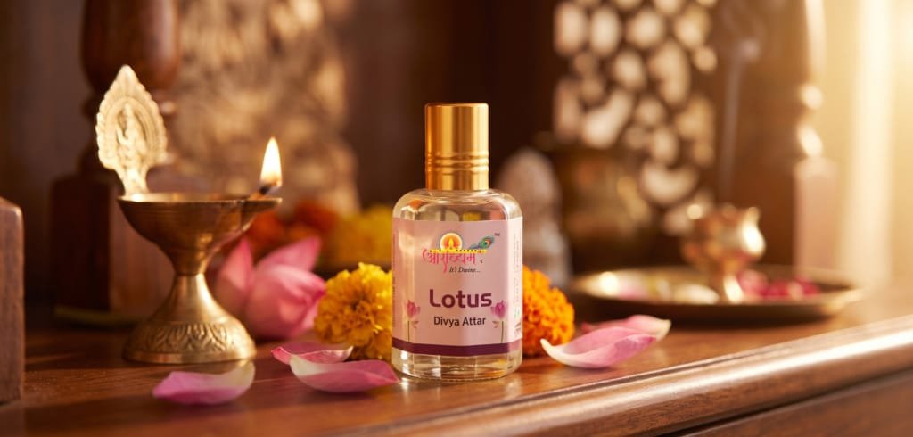 Lotus attar bottle beside a lit brass diya